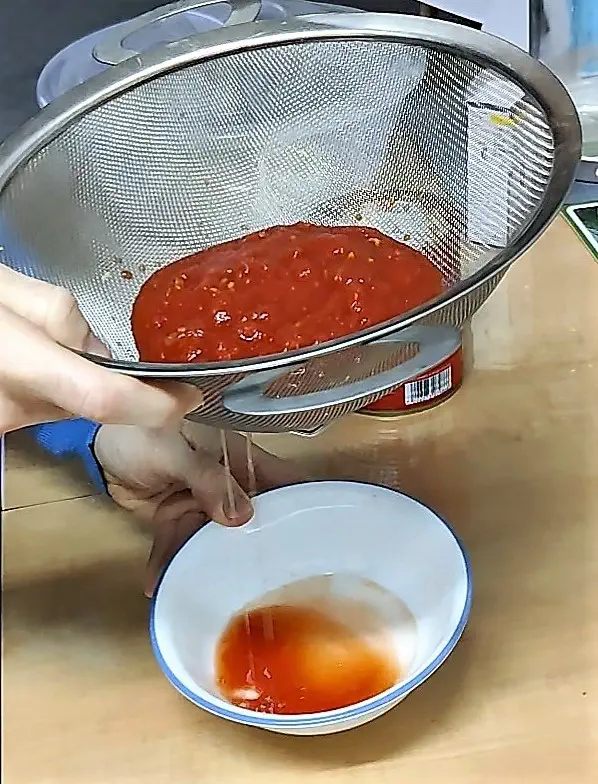 תמונה של סינון נוזלים מרוטב העגבניות להכנת פיצה שיקגו דיפ דיש